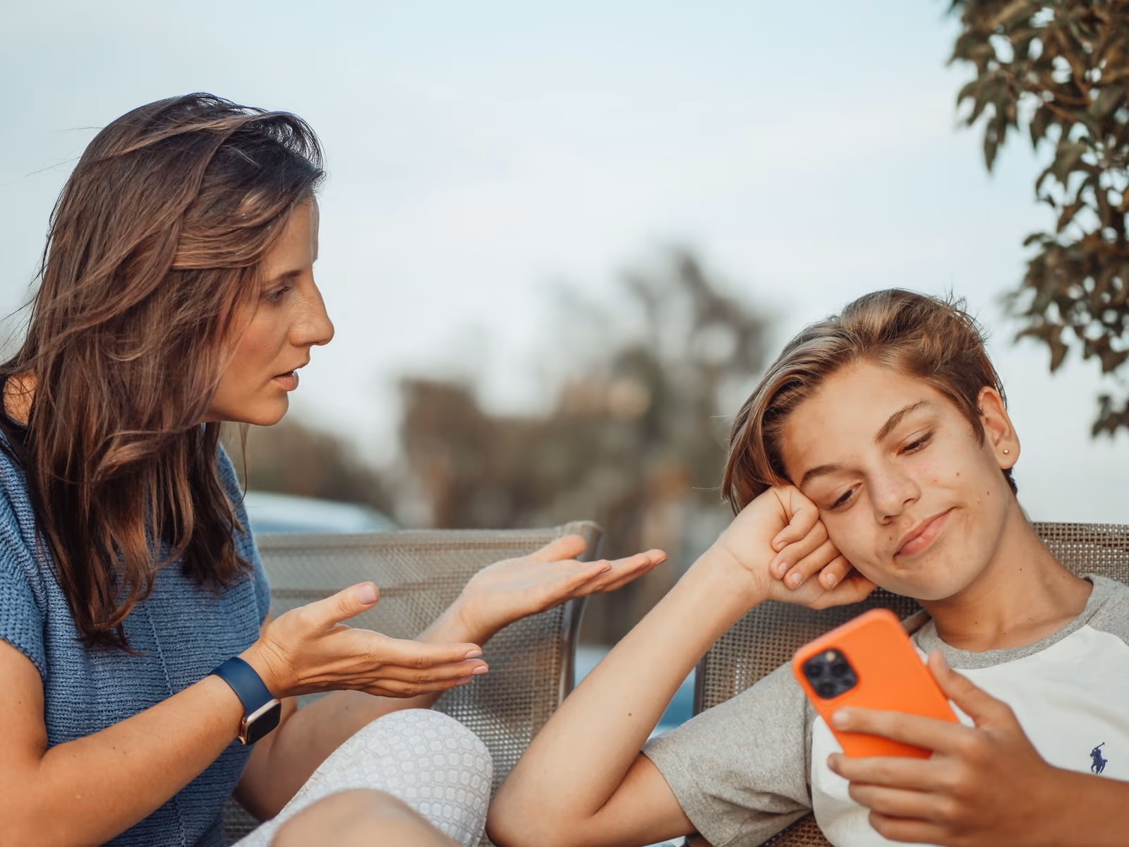 Nastolatek patrzy w telefon, kiedy mama próbuje z nim rozmawiać